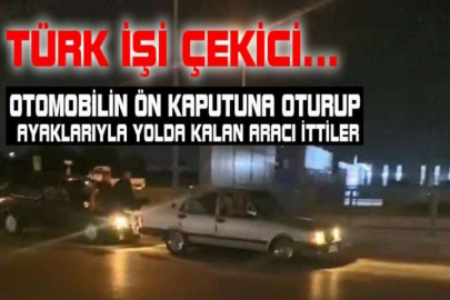 Otomobilin ön kaputuna oturup ayaklarıyla yolda kalan aracı ittiler